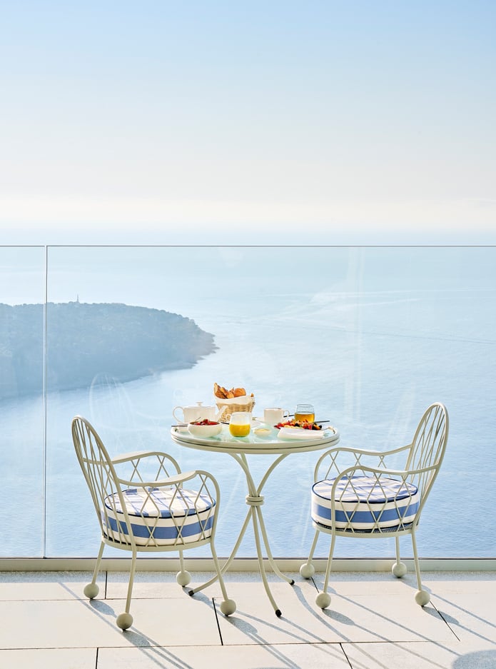 A table and two chairs with breakfast facing the sea.
