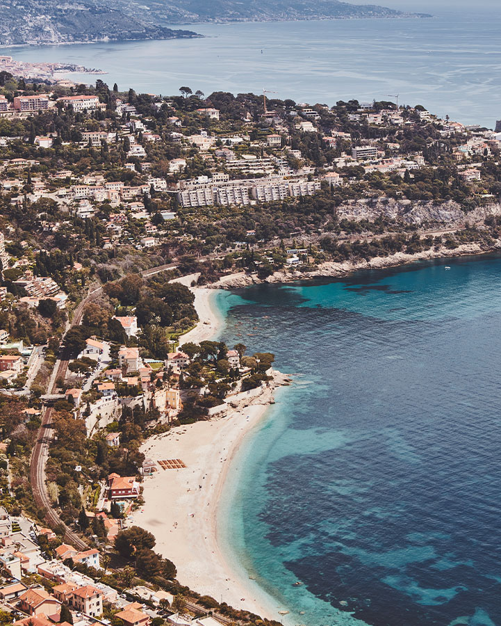 View over Monaco's coastline, with sea, beach, trees and buildings