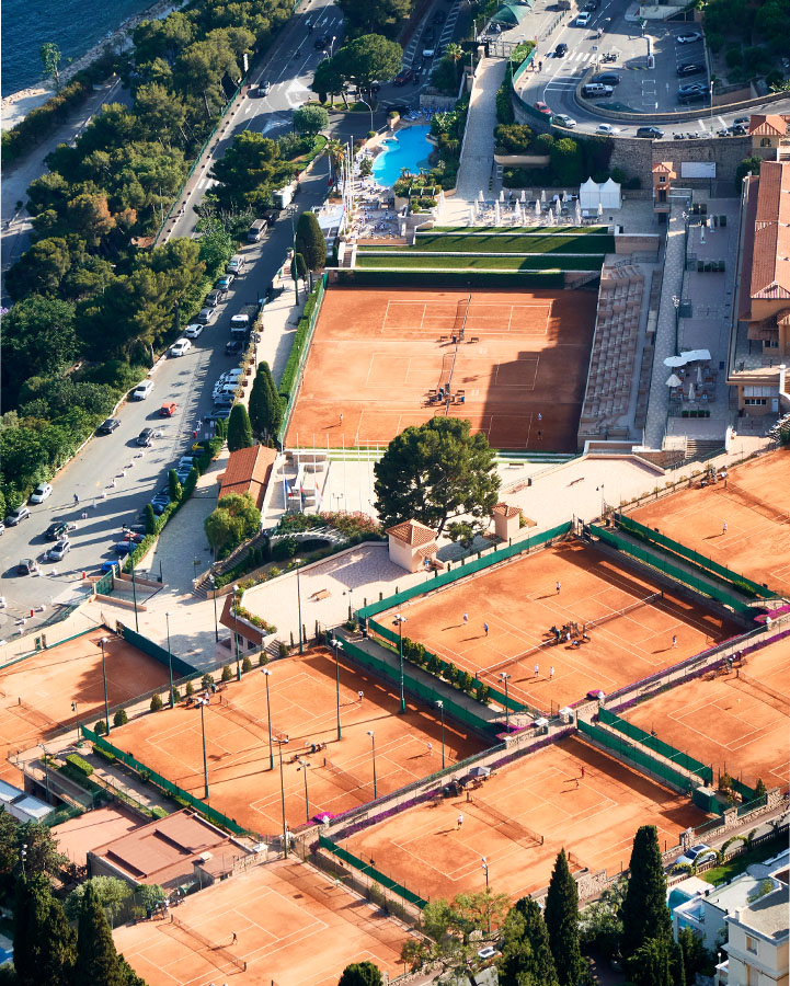 View over several tennis courts lined up in a row, with red AstroTurf