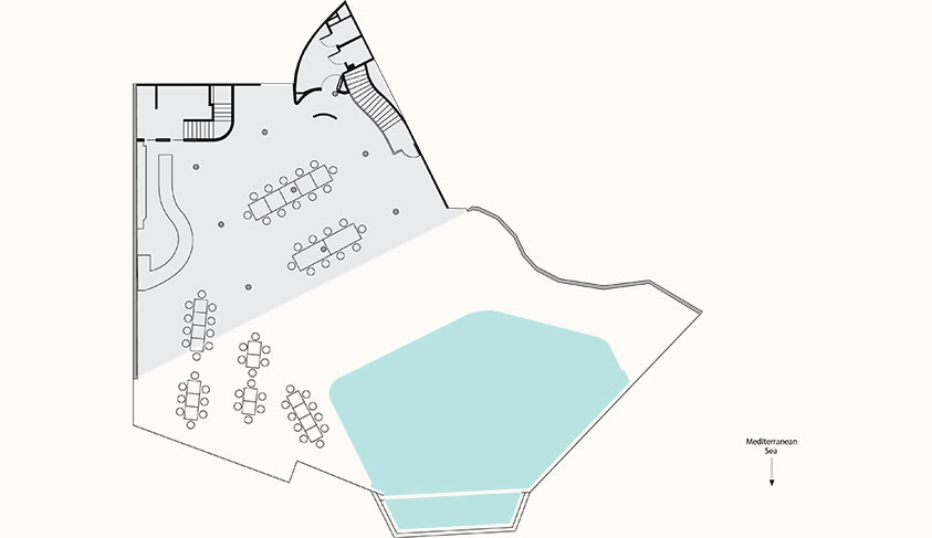 This floor plan depicts a seating arrangement around a large, irregularly shaped pool. The plan includes tables and chairs, and it is oriented with the Mediterranean Sea to the southeast.