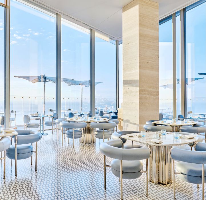 Salle de restaurant avec des tables dressées et vue sur la mer - Restaurant tables set up with a sea view