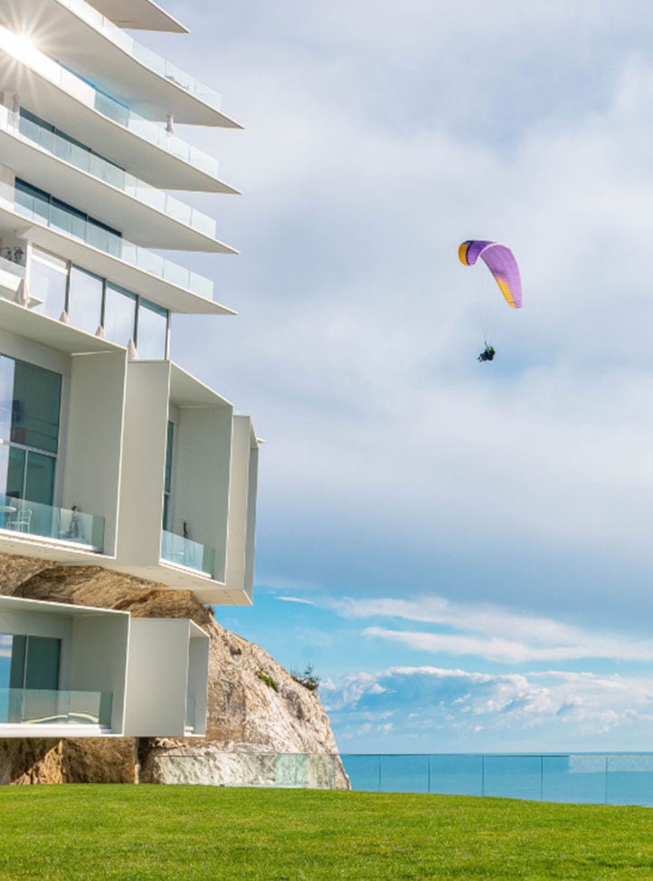 emme qui peint sur la pelouse face à l'hôtel avec un parapente dans le ciel - woman painting on the lawn in front of the hotel with a paraglider in the sky