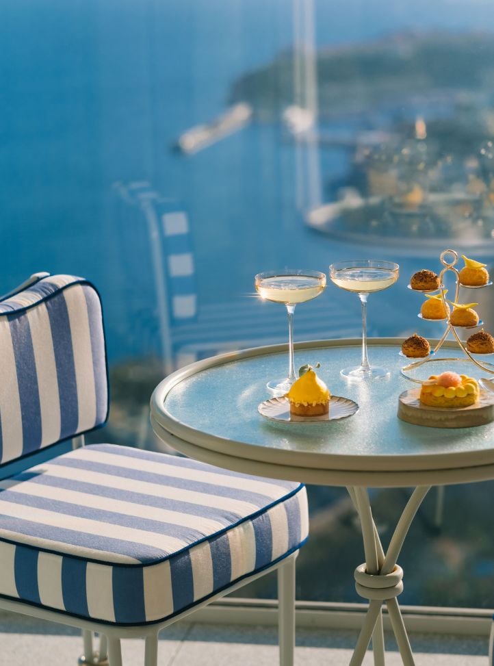 Chaise rayée bleue et blanche avec un table sur la terrasse vue mer, 2 verres de champagne et pâtisseries - Blue and white striped chair with a table on a sea view terrasse, 2 champagne glasses and pastries