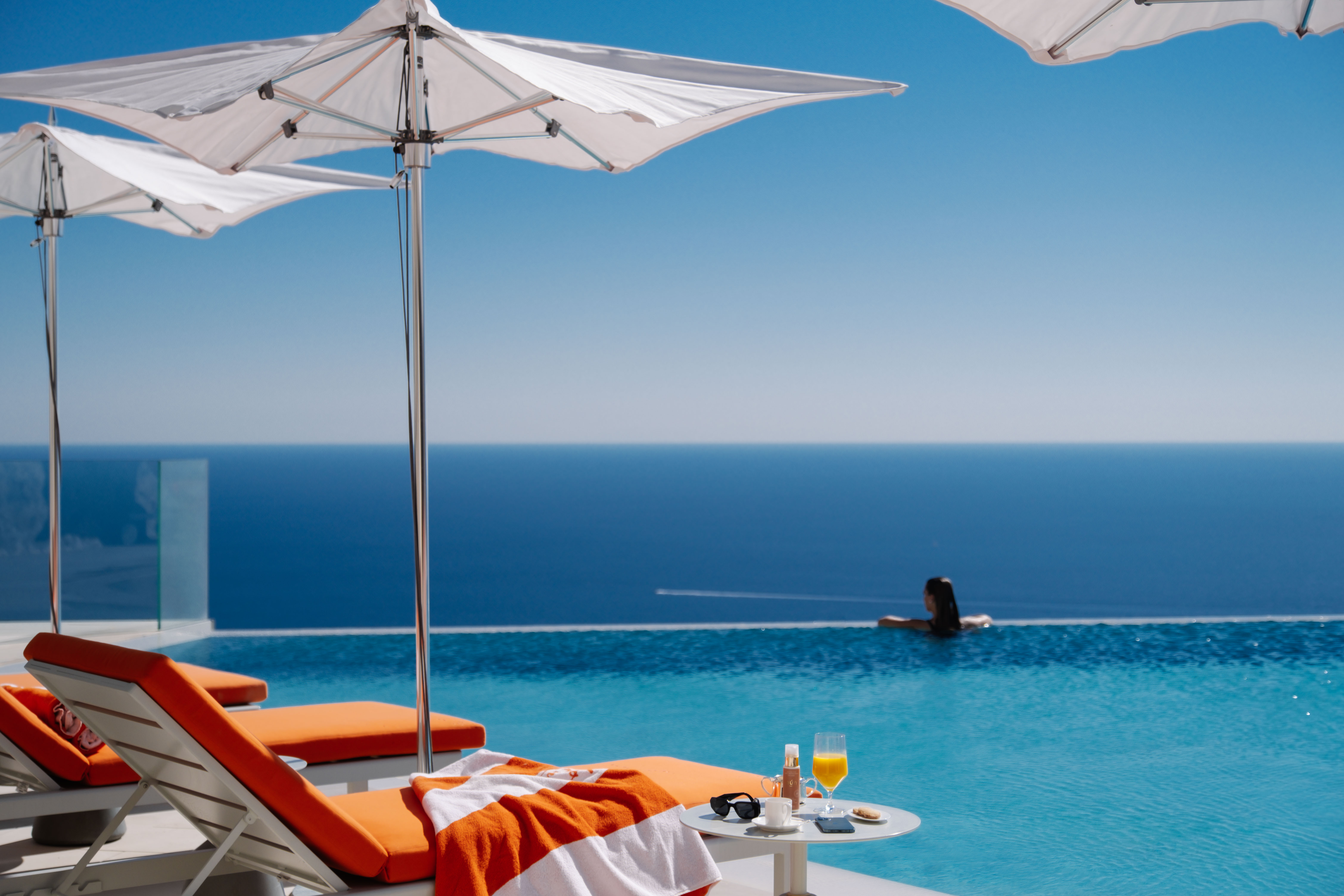 Transat au bord d'une piscine à débordement avec vue sur la mer - Sun lounger near an infinity pool overlooking the mediterannean