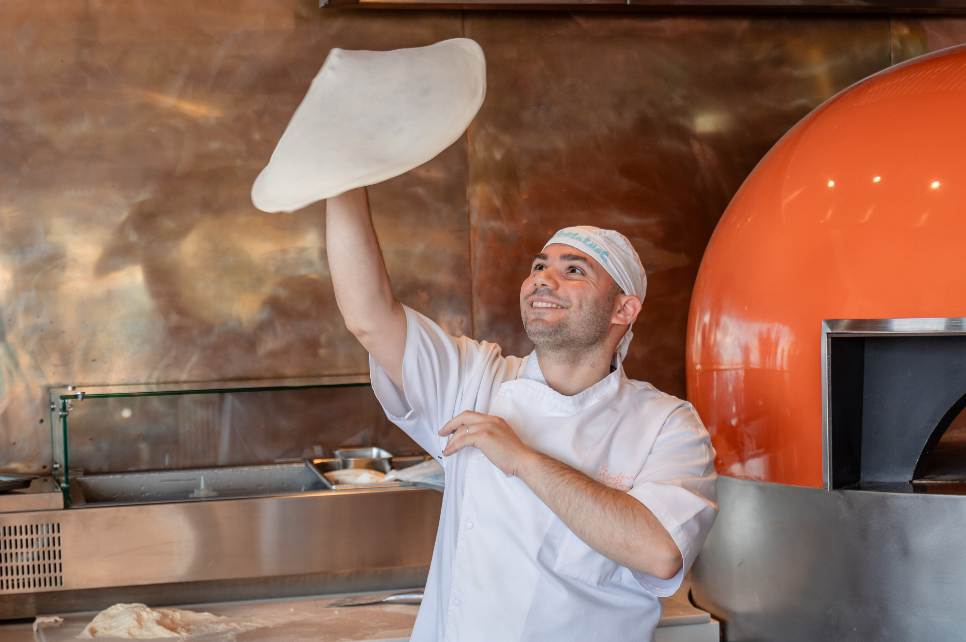 Pizzaiolo qui fait tourner un pizza dans les airs - Pizza chef twisting a pizza dough in the air