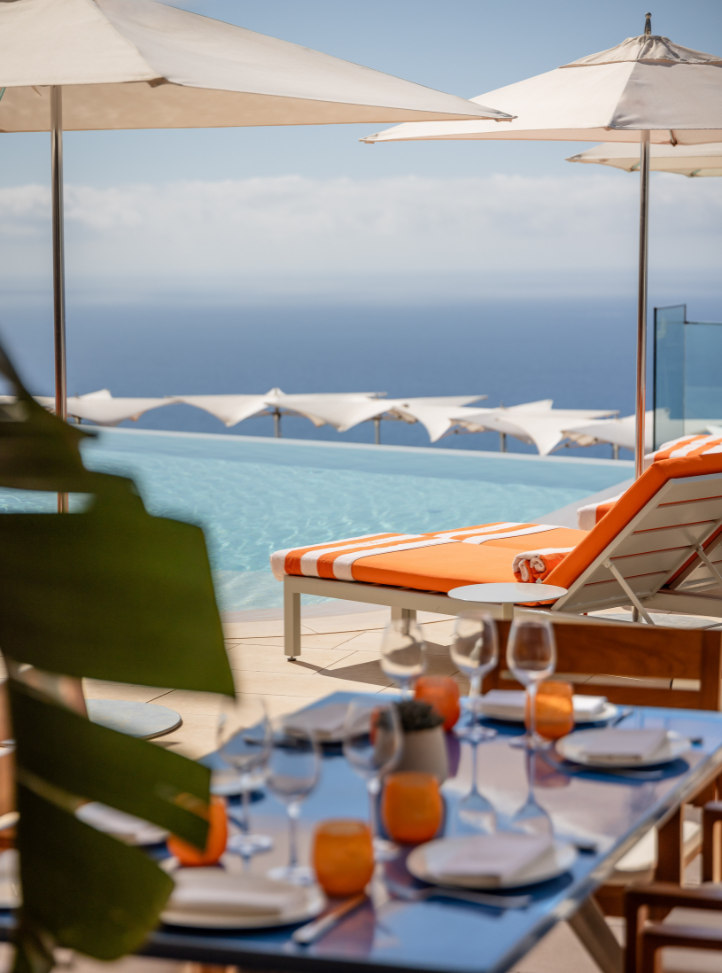 table de restaurant et transats orange devant une piscine avec vue mer - Restaurant table and orange sunbeds by the pool with sea view