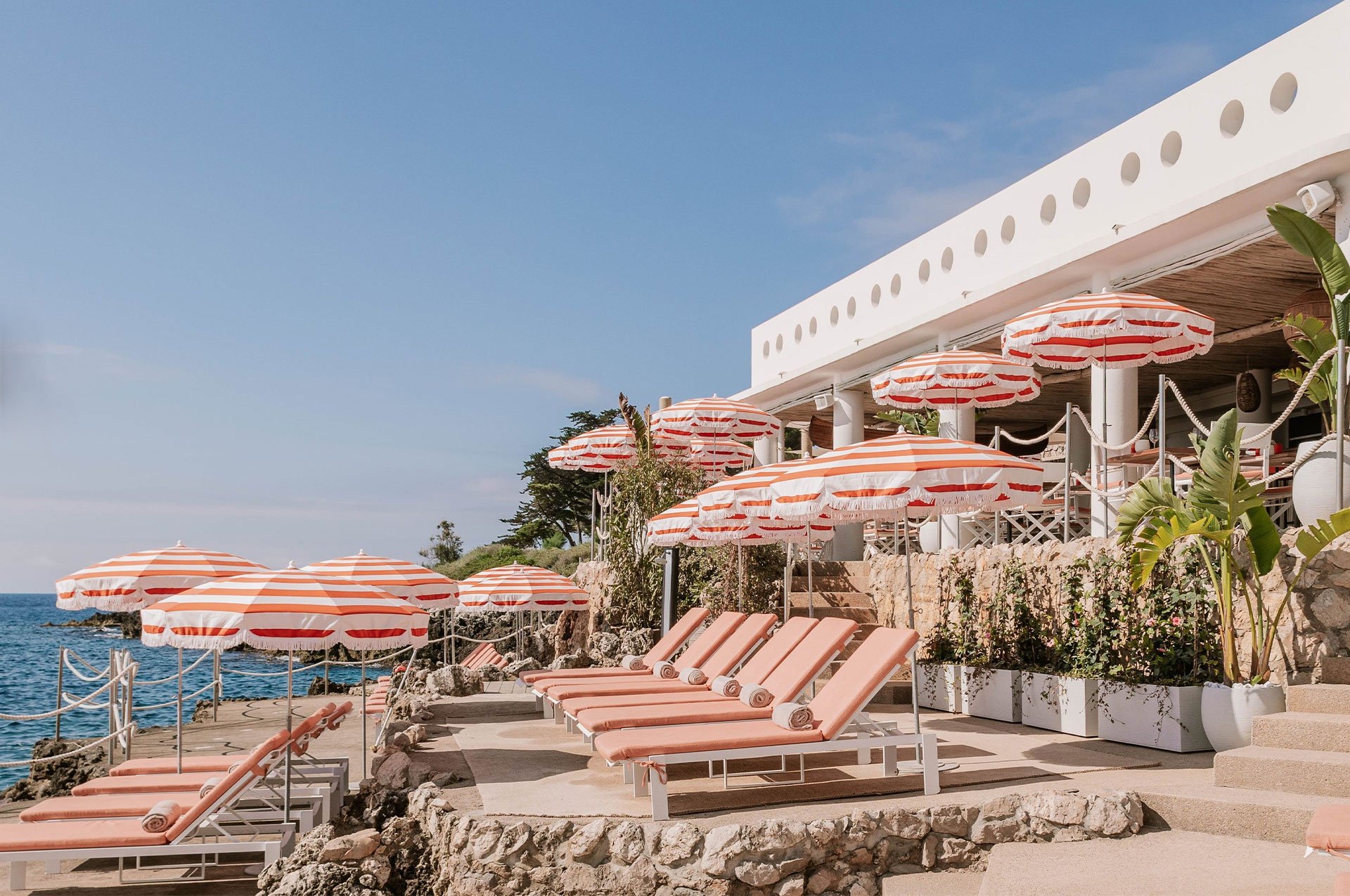 Maybourne La Plage: peach coloured sun beds in tiers facing the sea, with striped parasols to match.