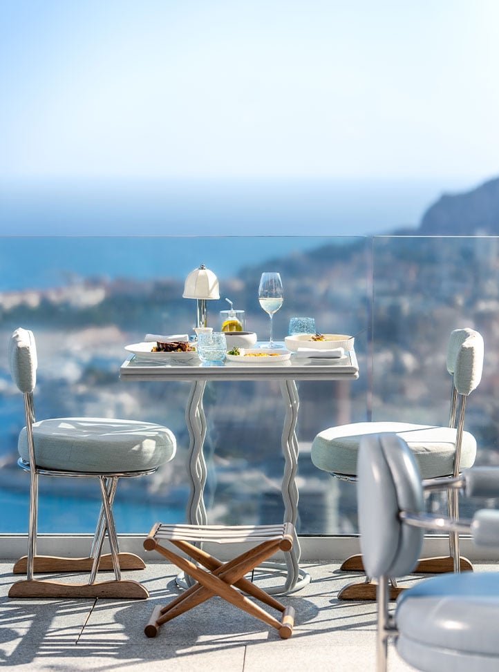 Dishes served at a table for two on the terrace at the Riviera Restaurant, with blue skies and far reaching sea views.