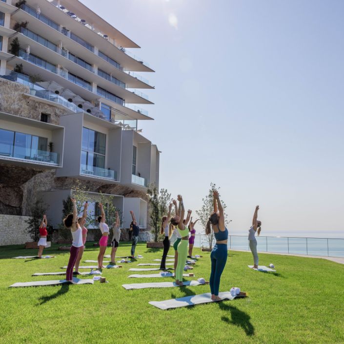 Groupe de personnes faisant du yoga sur la pelouse face à la mer - Group of people doing yoga on the lawn overlooking the sea